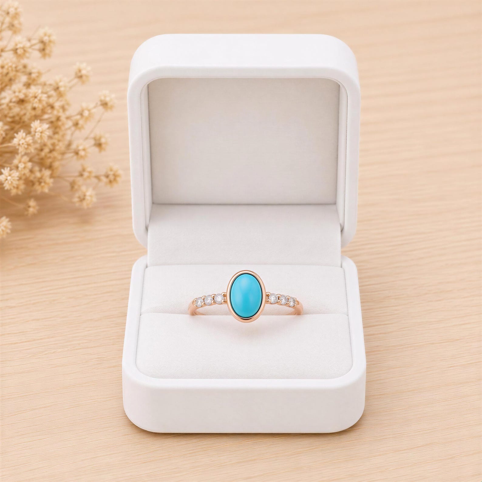 A white jewelry box containing a ring with a turquoise stone.